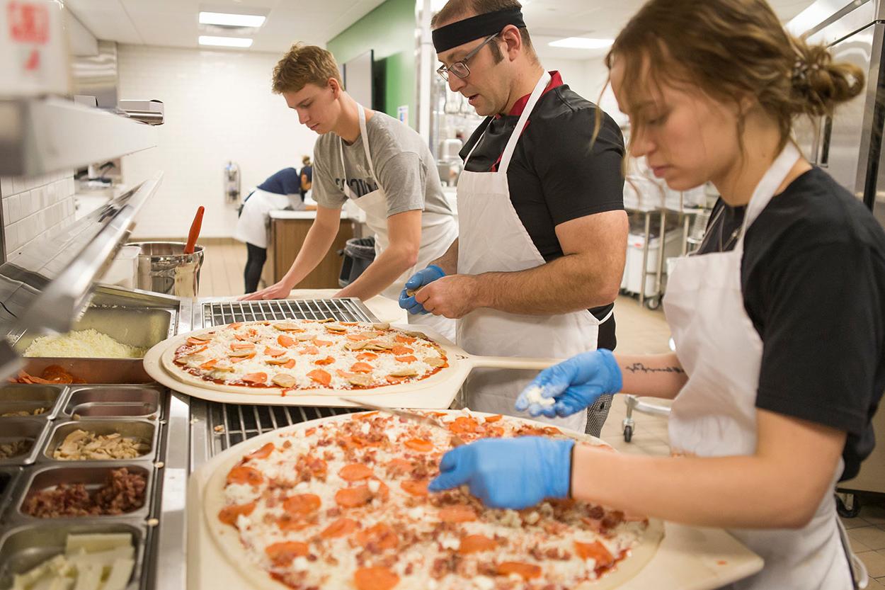 Students making pizza in the school kitchen.